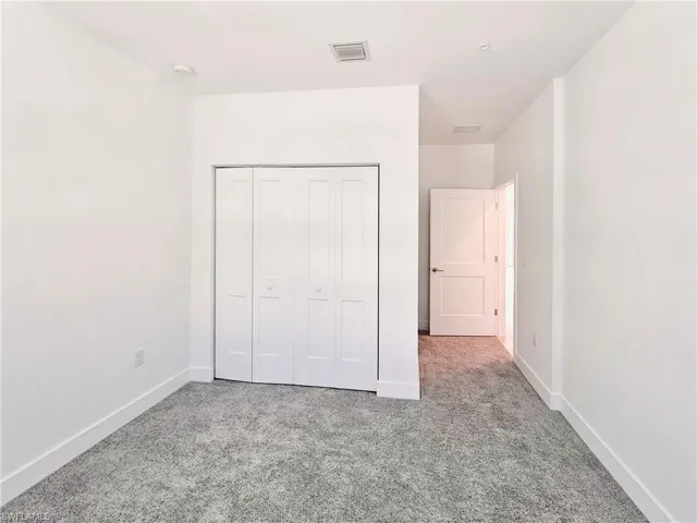Unfurnished bedroom featuring carpet floors, baseboards, and a closet