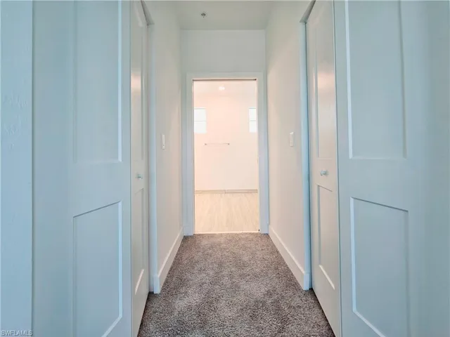 Corridor featuring carpet floors and baseboards