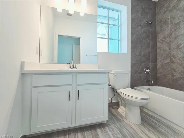 Full bath featuring toilet, vanity, baseboards, shower / bathtub combination, and wood finished floors
