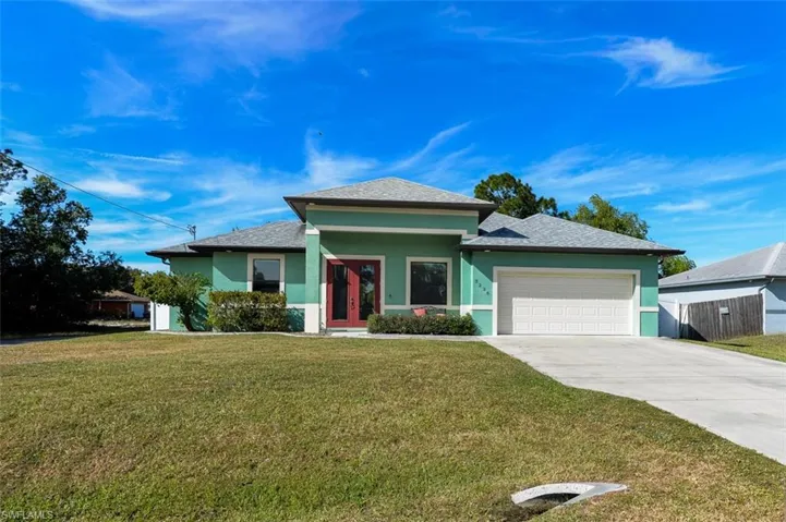 View of front of home with stucco siding, concrete driveway, a front lawn, and a garage