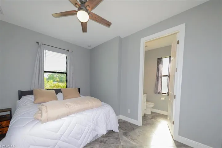 Bedroom with multiple windows, ceiling fan, and connected bathroom