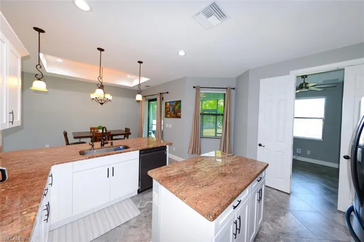 Kitchen with white cabinetry, decorative light fixtures, a peninsula, recessed lighting, and light stone countertops