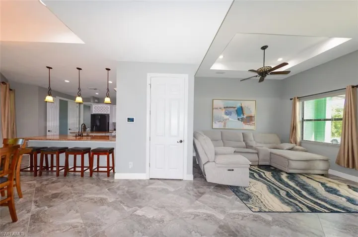 Living area featuring recessed lighting, a raised ceiling, light marble finish floors, and ceiling fan