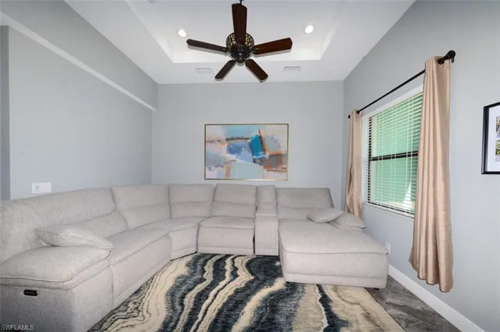 Living area with a tray ceiling, a ceiling fan, and recessed lighting
