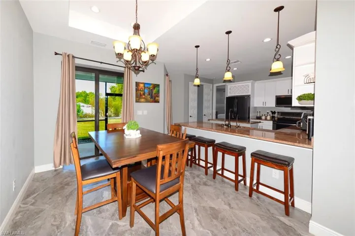 Dining area with a chandelier, recessed lighting, and a tray ceiling
