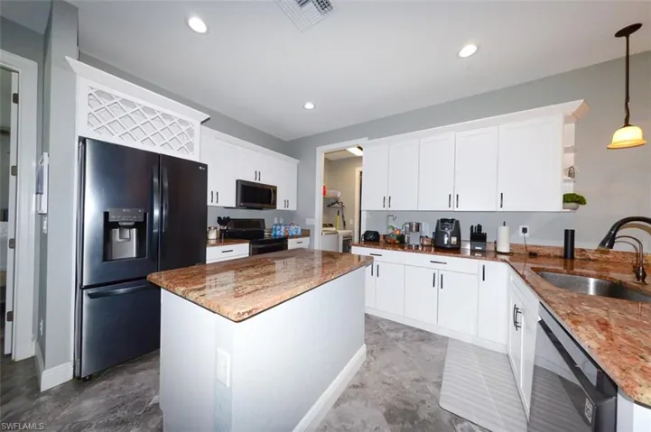 Kitchen featuring dark stone countertops, stainless steel appliances, pendant lighting, open shelves, and recessed lighting