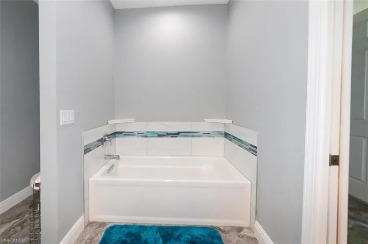 Bathroom with a bath and baseboards
