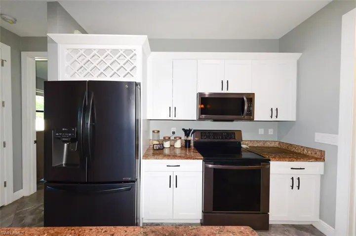 Kitchen featuring stainless steel appliances, white cabinetry, and dark stone counters