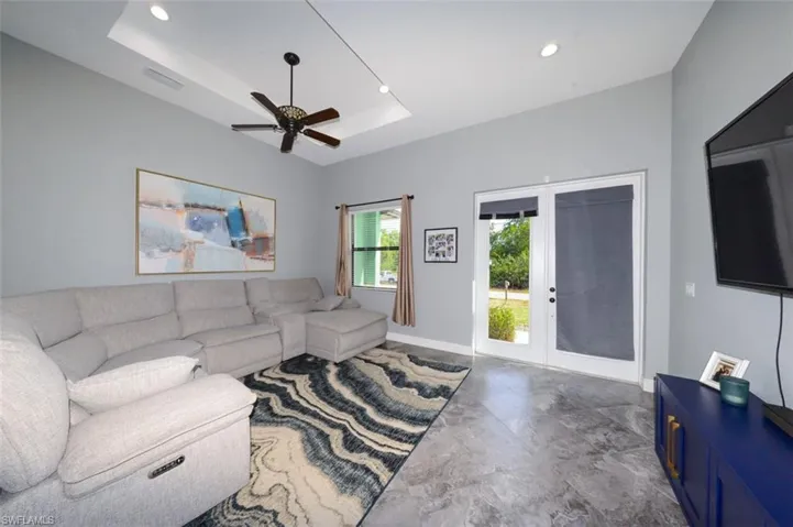 Living room with a tray ceiling, recessed lighting, a ceiling fan, and french doors