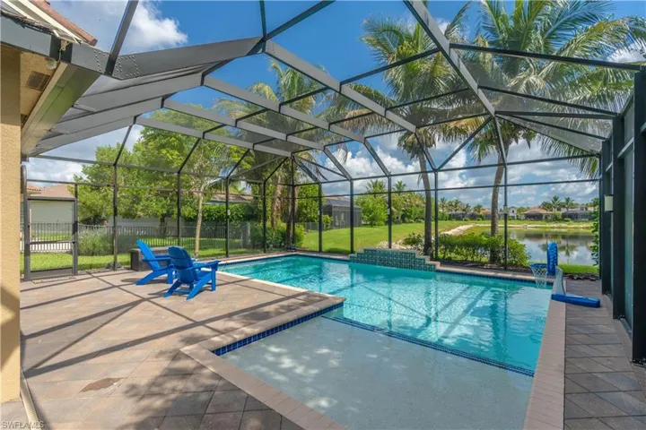 Screened outdoor living space featuring a swimming pool with an integrated sun shelf, a tiled water feature, and paver decking