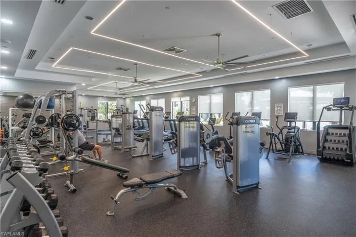Spacious fitness center featuring recessed lighting, ceiling fans, multiple exercise machines, weight racks, and rubber flooring