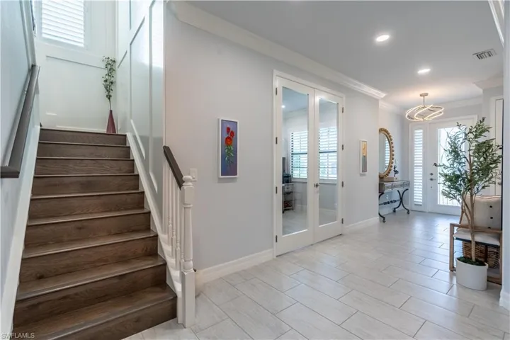Exquisite glass french doors open to office next to the beautiful staircase