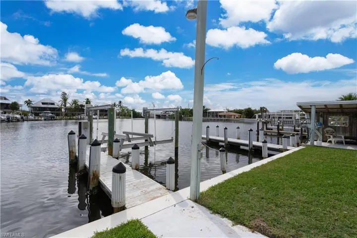 View of dock featuring a lawn and a water view