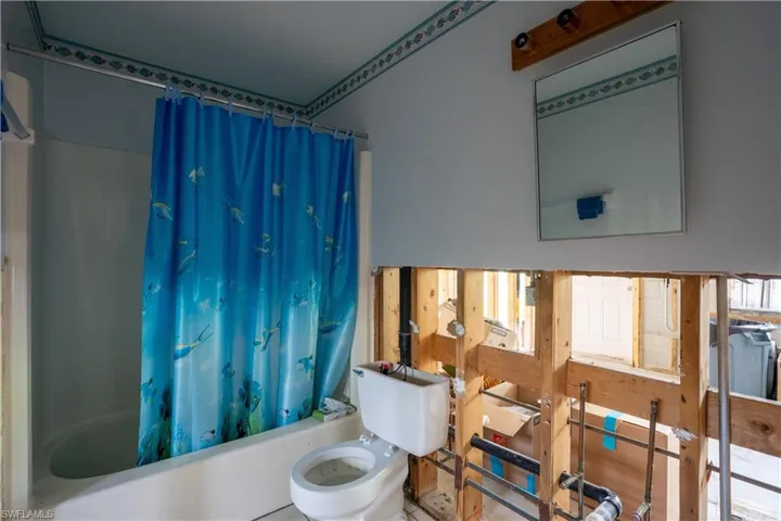 Bathroom with toilet and shower / tub combo with curtain