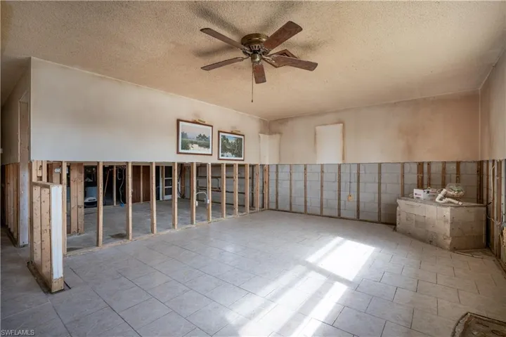 Spare room featuring a textured ceiling, ceiling fan, and tile walls