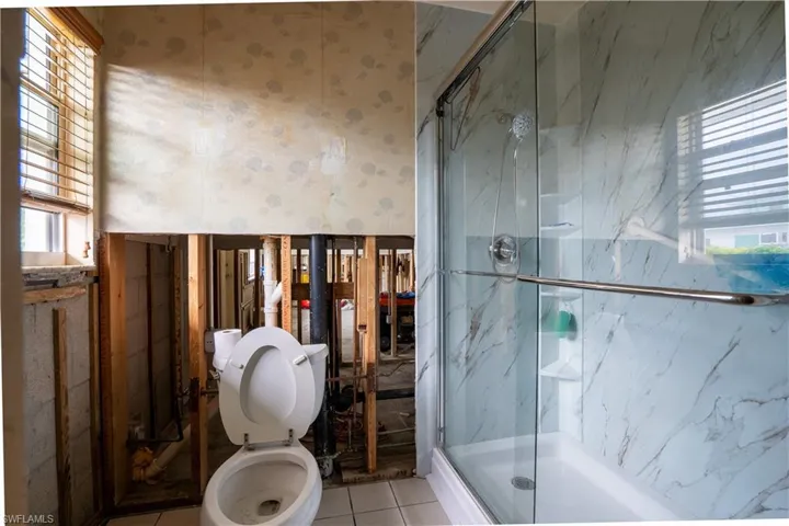 Bathroom featuring tile patterned floors, toilet, and an enclosed shower