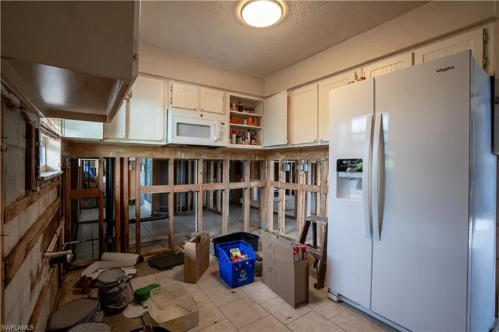 Kitchen featuring white cabinetry, white appliances, and a textured ceiling