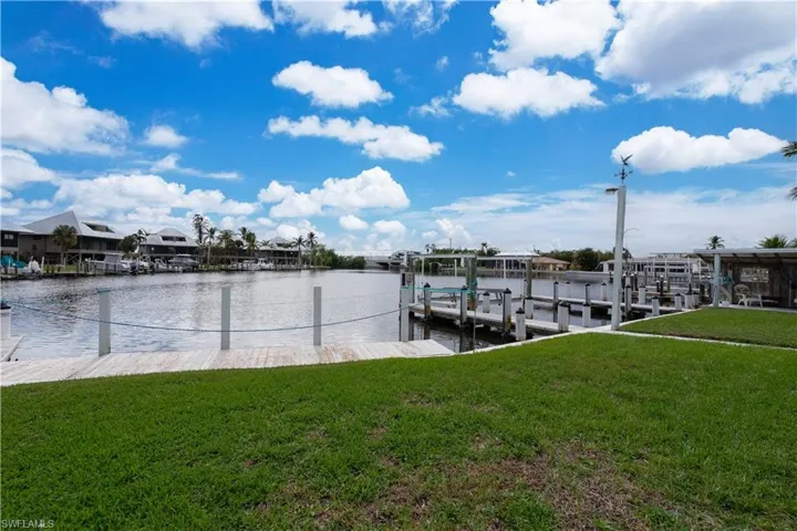 View of dock featuring a lawn and a water view