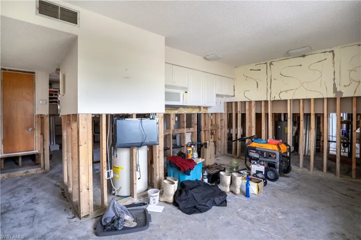Misc room featuring gas water heater, a textured ceiling, and concrete floors