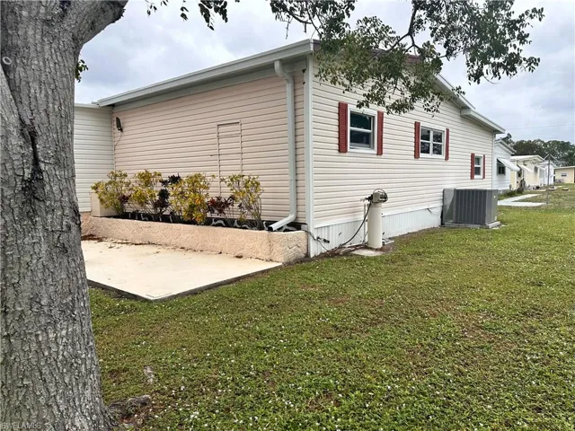 View of property exterior with a patio, a yard, and central AC