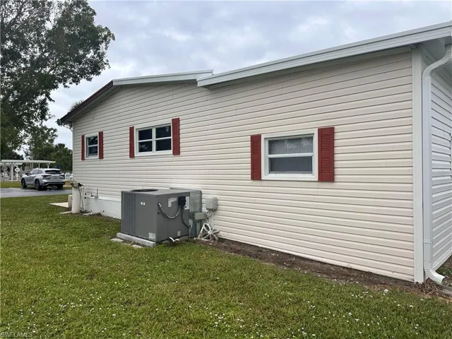 View of side of property featuring central AC unit and a lawn