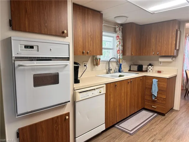 Kitchen with sink, light hardwood / wood-style flooring, and white appliances