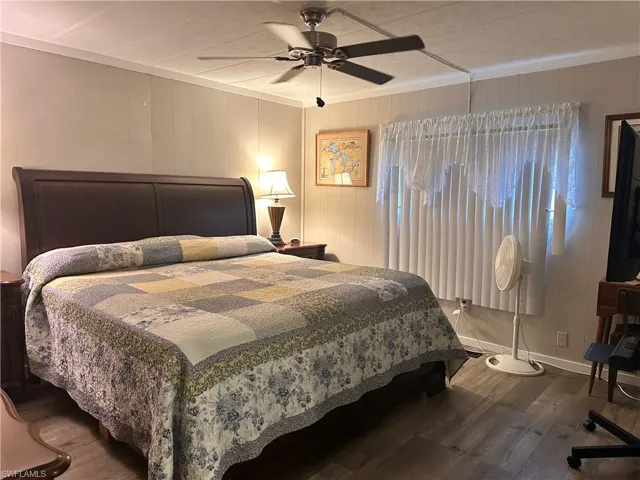 Bedroom with ceiling fan, dark hardwood / wood-style flooring, and crown molding
