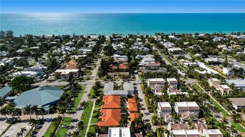 Aerial view of property and surrounding area featuring nearby suburban area and a large body of water