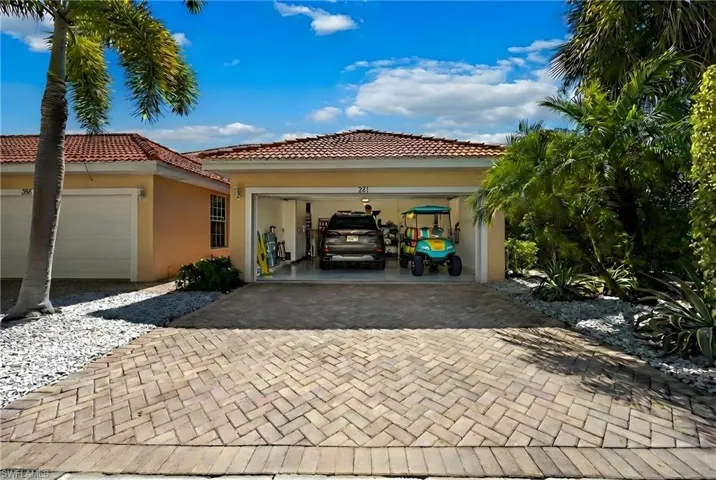 View of side of home featuring stucco siding, decorative driveway, a garage, and a tiled roof