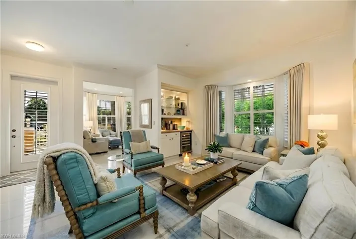 Tiled living room with plenty of natural light, beverage cooler, and ornamental molding
