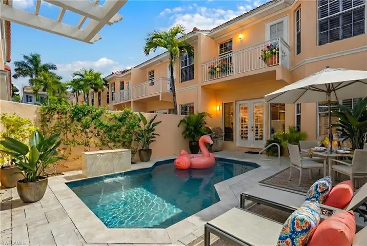 View of pool featuring french doors, patio surround, outdoor dining area, and a balcony