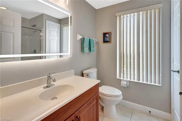 Bathroom featuring tile patterned flooring, an enclosed shower, vanity, and toilet
