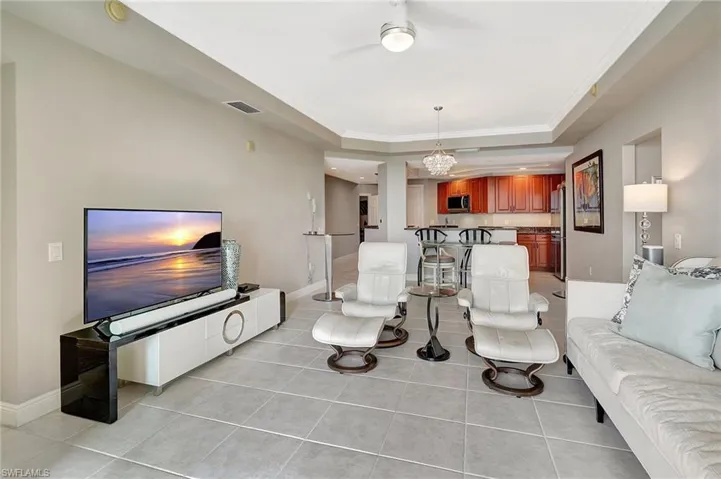 Living room with ornamental molding, a raised ceiling, and light tile patterned flooring