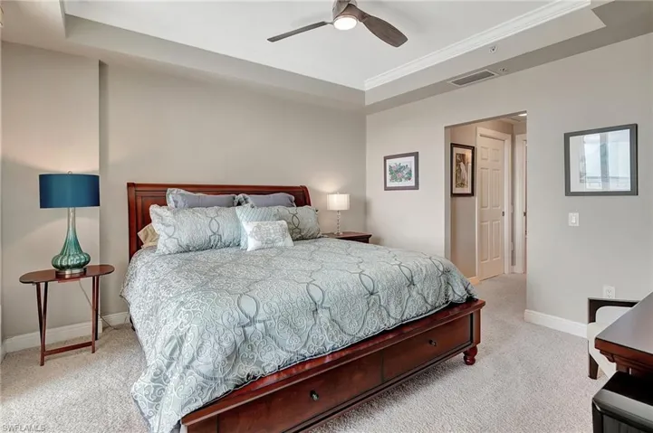 Carpeted bedroom featuring crown molding, a tray ceiling, and ceiling fan