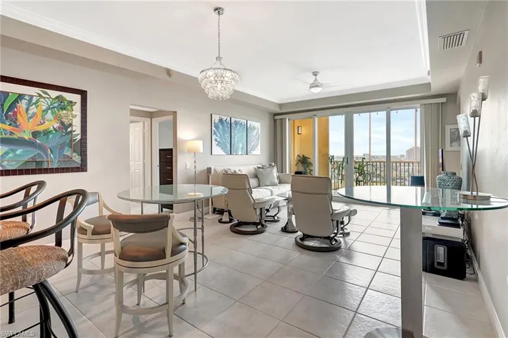 Living room with light tile patterned floors, crown molding, and ceiling fan with notable chandelier