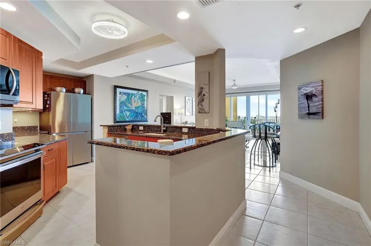 Kitchen featuring light tile patterned flooring, stainless steel appliances, dark stone counters, and sink