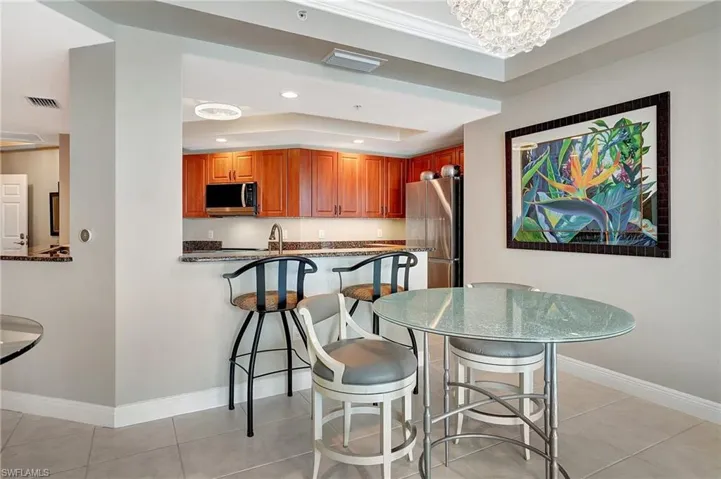 Kitchen featuring light tile patterned floors, appliances with stainless steel finishes, a kitchen breakfast bar, kitchen peninsula, and a tray ceiling