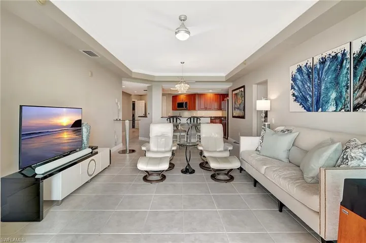 Tiled living room featuring ornamental molding and a raised ceiling