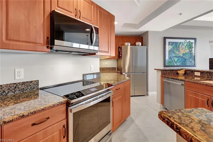 Kitchen with light tile patterned flooring, stainless steel appliances, and dark stone counters