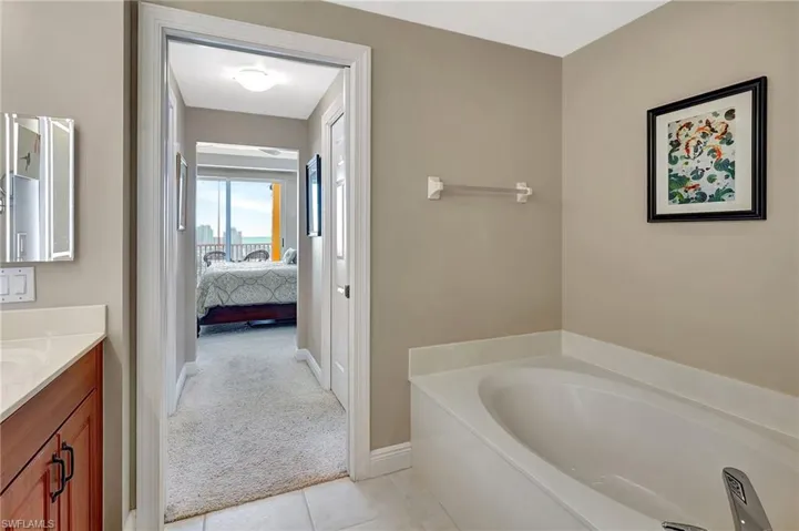 Bathroom featuring tile patterned flooring, vanity, and a bath