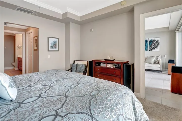 Carpeted bedroom featuring crown molding and ensuite bathroom