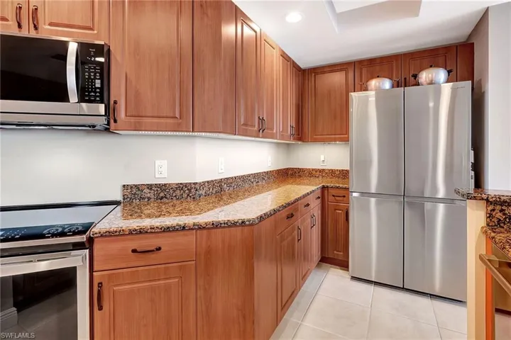 Kitchen featuring light tile patterned floors, stainless steel appliances, and light stone counters