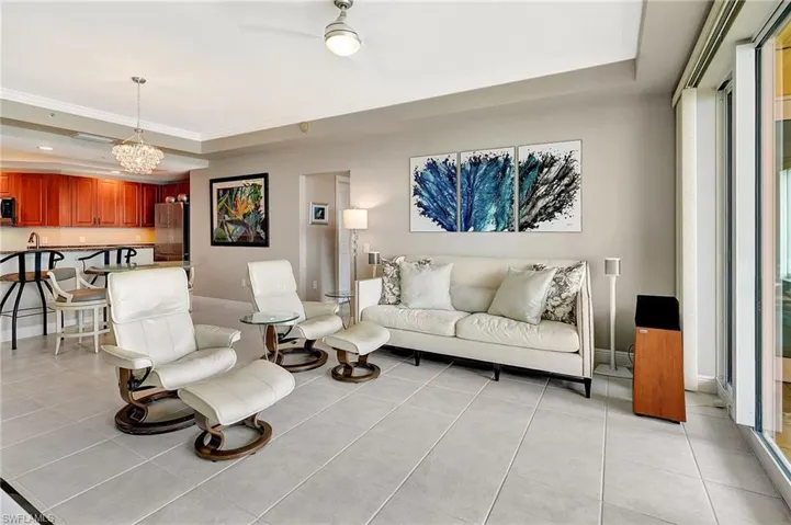 Tiled living room with a notable chandelier and a tray ceiling