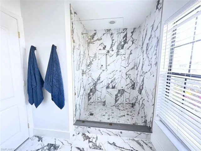 Ensuite bathroom featuring large walk-in marble-look tile shower