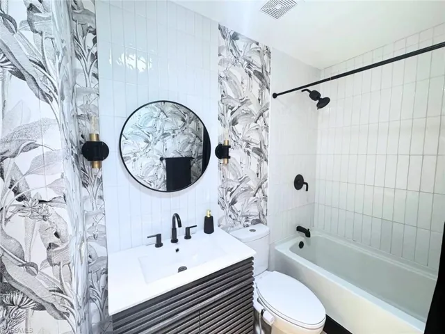 Front bathroom featuring custom tile work, vanity, and lighting (2024)
