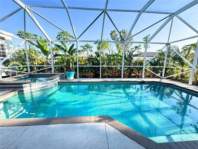 View of pool with connected waterfall hot tub and lanai