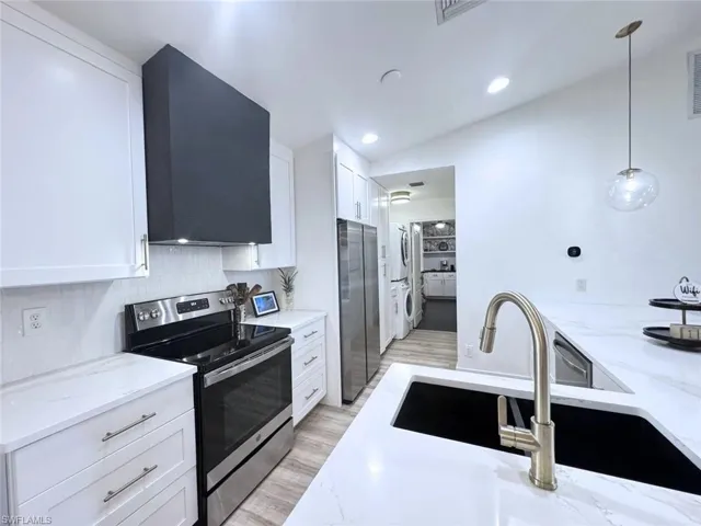 Kitchen featuring wall chimney range hood, easy-access washer and dryer and walk-in pantry