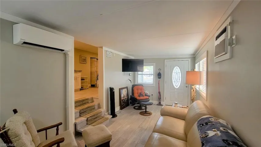 Living room with wood finished floors and an AC wall unit