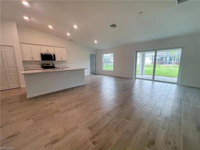 Kitchen with white cabinets, light wood-style flooring, a kitchen island with sink, open floor plan, and recessed lighting