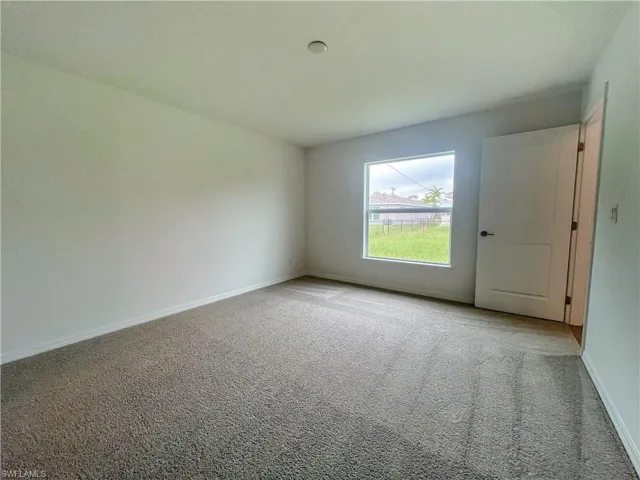 Carpeted spare room featuring baseboards
